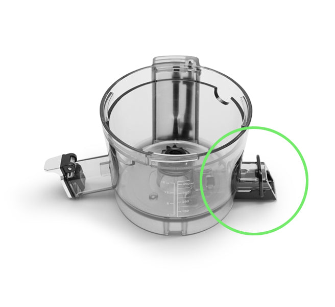 A transparent food processor bowl with measurement markings is shown from above. A green circle highlights the Pulp Outlet Loop, a juicer accessory for the Nama J2 Cold Press Juicer, located on the right side of the bowl.